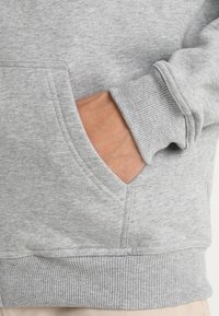 Gray sweatshirt featuring a front pocket, ribbed cuffs, and hem, with a soft texture and casual design. Visible stitching accents.