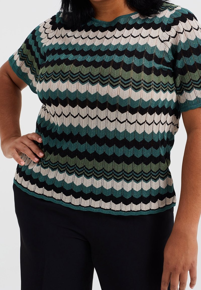 Multicolored short-sleeve top with a zigzag pattern in teal, green, black, and cream; crafted from a textured, knit material.