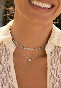 Collana in argento a più strati con una catena più corta caratterizzata da un pendente a forma di lettera "A". Finitura in metallo liscia, design moderno e texture delicata.