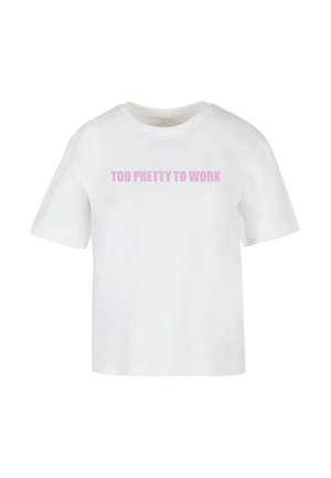 Witte t-shirt met korte mouwen en een ronde hals, met de tekst "TE MOOI OM TE WERKEN" in lichtroze over de borst. Zacht katoen materiaal.