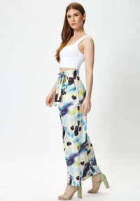 White cropped tank top paired with wide-leg pants featuring a colorful abstract pattern in blue, yellow, and purple. Designed with a tied waist.