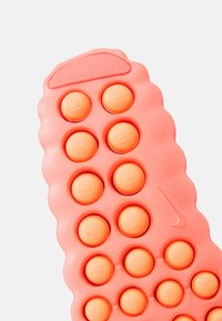 Εσωτερικός πάτος Nike με απαλό ροζ υπόβαθρο, ανυψωμένα πορτοκαλί κυκλικά μαξιλαράκια, υφή στην επιφάνεια και ελαφρύ κυματιστό σχέδιο.