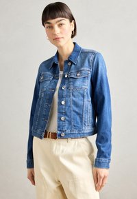 Giubbotto di jeans in blu chiaro con design classico, dotato di chiusura a bottoni, tasche sul petto e maniche lunghe. Texture morbida e stile corto.