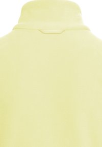 Παλιά κίτρινη φλις ζακέτα, όψη από πίσω με ανασηκωμένο γιακά και μικρό υφασμάτινο λουράκι κάτω από τον γιακά.