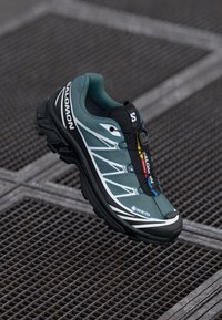 GORE-TEX wandelschoen in turquoise en zwart, met een gevoerde zool, gestroomlijnd ontwerp en reflecterende accenten. Gemêleerd stoffen bovenwerk.