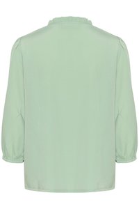 Mintgrön blus med rund halsringning, volangdetaljer och korta puffärmar, tillverkad av ett smidigt tyg med en avslappnad passform.