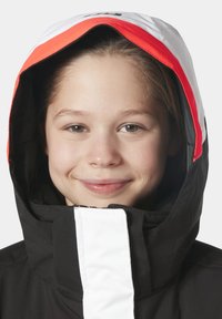 Černá bunda s bílou a červenou kapucí. Obsahuje přední zip a vysoký límec, navržena pro teplo a ochranu v chladném počasí.