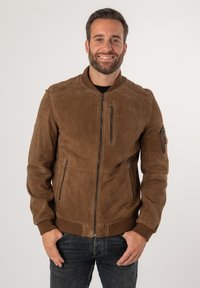 Giubbotto bomber in suede marrone con chiusura frontale a zip, polsini a costine e tre tasche con zip. Presenta una trama liscia e un design aderente.
