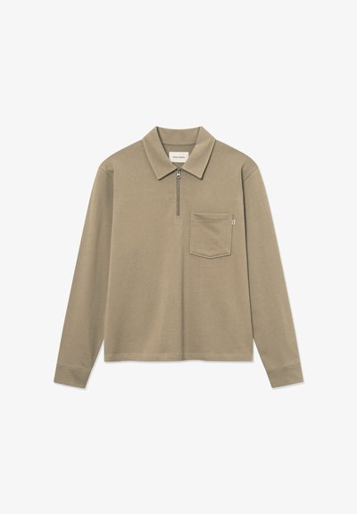 Hosszúujjú pólóing khaki színű anyagból, elülső cipzárral, gallérral és egyetlen mellzsebbel, amelynek élei hajtva vannak.