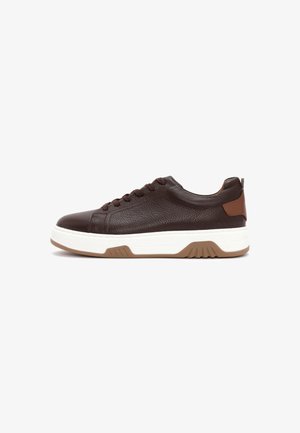 Dark brown leather sneaker with textured surface, lace-up closure, white thick sole with brown tread, and tan heel accent.