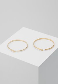 Gold-plated hoop earrings, circular shape, smooth texture, featuring a secure clasp closure. Clean design on a light gray display.