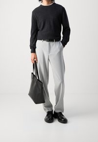 Dunkelgrauer Strickpullover, hellgraue maßgeschneiderte Hose, schwarze Lederschuhe und eine schwarze Tote-Bag. Klassischer Stil mit lockerer Passform und glatter Textur.