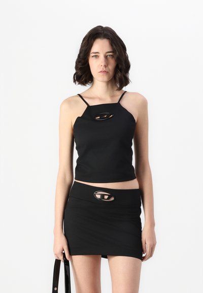 Haut crop noir à bretelles fines et jupe mini, tous deux comportant des découpes. Fabriqué en tissu lisse au design ajusté.