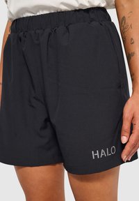 Svarta shorts i strukturerad material med resårmidja, sidofickor och en silverfärgad logotyp som står "HALO" på den nedersta kanten.