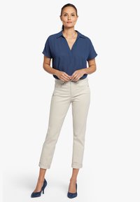 Námořnická blůza s krátkým rukávem a výstřihem do V, spojená s vyhrnutými světle béžovými kalhotami. Modré semišové lodičky dokončují outfit.