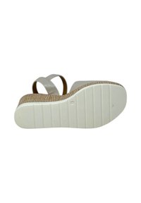 Sandal bianca con tacco a zeppa, caratterizzata da una suola testurizzata e due fasce larghe. La soletta ha una texture naturale intrecciata.