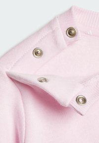 Col au tricot rose clair avec boutons-pression, présentant une texture douce et des bords côtelés. Comprend une couche intérieure en velours pour le confort.