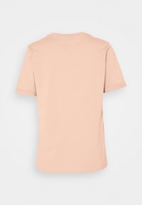 T-shirt court à manches courtes de couleur pêche claire avec un col rond, texture lisse et dos uni. Aucun motif ni accent visible.