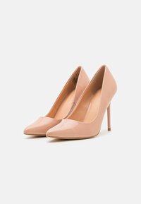 Vaaleanpunaiset patenttivaatteiset korkokengät, joissa on terävät varpaat ja ohuet stiletto-korkokengät. Tasainen pinta, jossa on kiiltävä viimeistely.