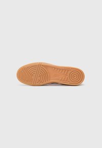 ASICS hardloopschoen met een rubberen buitenzool, met een gestructureerd gripontwerp en cirkelpatronen. Voornamelijk oranje van kleur.