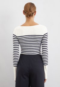Long-sleeve top featuring a navy and white striped design with a wide scoop neckline. Soft, lightweight fabric with a fitted silhouette.