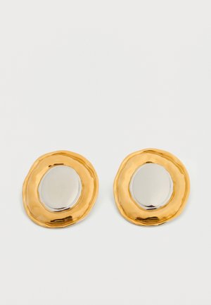 Arany és ezüst fülbevalók egy szabálytalan, texturált óvalis formával és polírozott felületekkel. Jelentős színkontraszt.