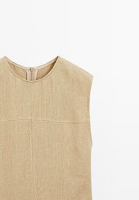 Haut sans manches en lin beige texturé avec col rond et fermeture éclair au dos, présenté sur fond blanc.