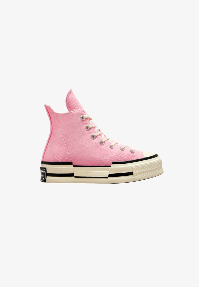 High-top sneakers in pink canvas with silver eyelets, white laces, and a thick cream sole featuring black accents and a textured toe cap.