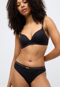 Čierna podprsenka s tvarovanými košíčkami a nastaviteľnými ramienkami s logom. Zodpovedajúce čierne bikini nohavičky s kontrastným pásom s logom.