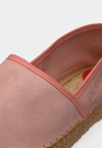 Ροζ σουέντ εσπαντρίγια με κοράλλι διακοσμητική λεπτομέρεια, πλεκτή σόλα από σχοινί τζούτης και ανάγλυφες επιγραφές "LOVE MOSCHINO" στην εσωτερική πλευρά.