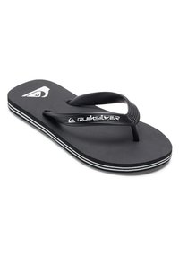 Musta läppäjalkine, jossa on tekstitetty sisäpohja, mustat kumihihnat ja valkoiset yksityiskohdat pohjassa. Hihnassa on Quiksilver-logo.