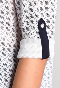 Camicia button-up con un motivo geometrico in bianco e nero, con polsini e dettagli dei bottoni in contrasto blu navy. Tessuto in cotone o simile.