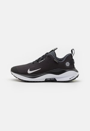 Chaussure de course Nike noire avec un swoosh blanc, une semelle blanche, un onglet au talon et un logo sur le côté, vue de profil droit sur fond blanc.