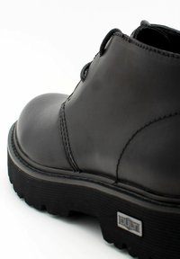 Stivaletto in pelle nera con punta arrotondata, suola texturizzata e cuciture rinforzate. Presenta una placca con logo sul lato e un design con lacci.