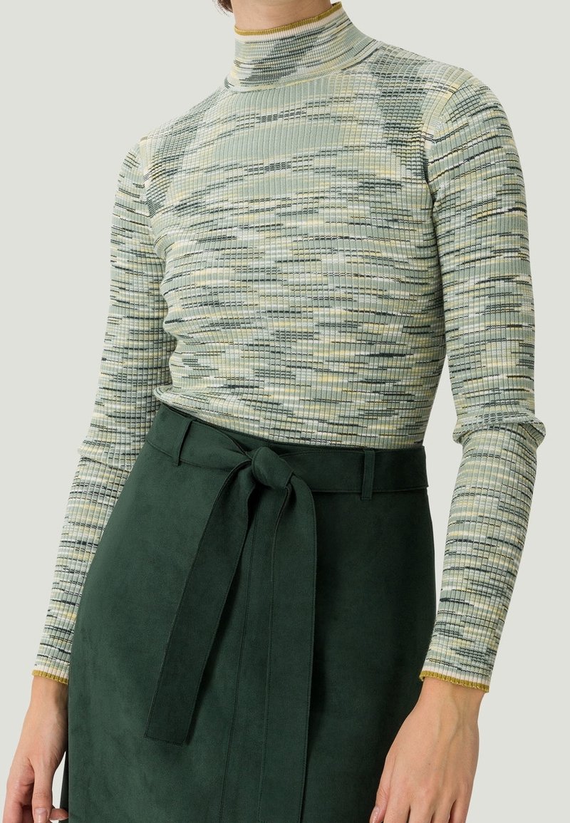 Ribbed turtleneck sävyissä vihreä ja beige, jossa on teksturoitu kuvio, yhdistettynä tummanvihreään mokkahuuhteeseen, jossa on sidottu vyötäröyksityiskohta.