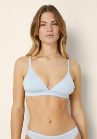 Ljusblå bralette med djup V-ringning och tunna band, tillverkad av mjukt tyg med sömlös design för komfort.