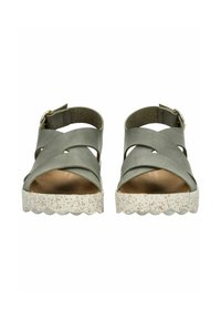 Zelené kožené sandály s křížovými pásky, otevřenými špičkami a strukturální bílou podrážkou s vlnitým okrajem a tečkovaným vzorem.