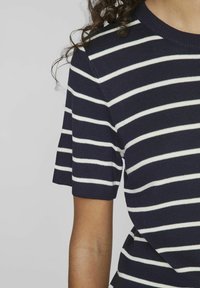 Námořnické modré a bílé pruhované pletené tričko s krátkým rukávem a kulatým výstřihem. Textura je hladká s žebrovaným povrchem.