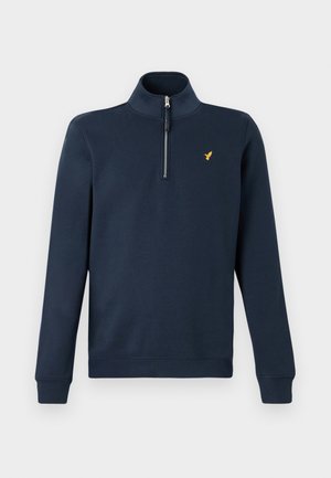 Mørkeblå langærmet pullover med kvart lynlås og lille gul fuglelogo på venstre bryst, ribstrikkede manchetter og kant.