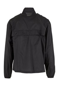 Giacca nera con maniche lunghe, presenta un collo alto, un design posteriore a strati e polsini elasticizzati, realizzata in un tessuto liscio e leggero.