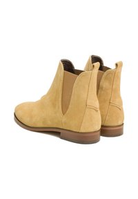 Bottines en suède beige clair avec panneaux latéraux élastiques, bout arrondi et talon bas en bois, présentant une texture lisse et un design simple.