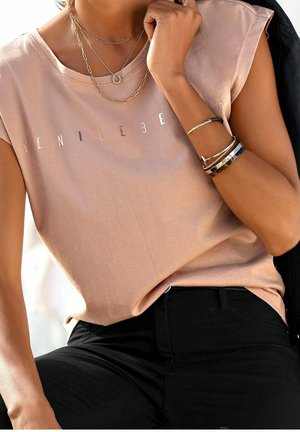 Top de manga corta en rosa claro con "VENICEBEACH" impreso en el pecho en una fuente degradada. Combinado con pantalones ajustados negros y collares en capas.