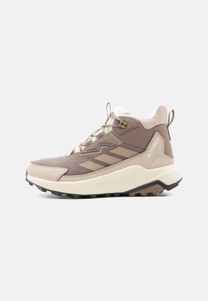 Светлокафяв и бежов висок спортен обувка Adidas Terrex с текстурирана подметка, връзки отпред и ленти за издърпване на езика и петата.