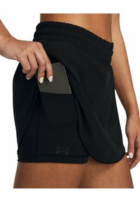 Shorts sportivi neri con cintura elastica, dotati di una tasca laterale che contiene uno smartphone. Texture liscia e dettagli di cucitura a contrasto.