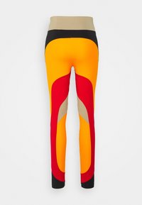 Leggings de cintura alta hechos de una tela elástica que presenta colores vibrantes: naranja, rojo, beige y negro, con un diseño abstracto de bloques de color.