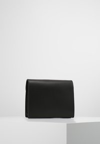 Borsa a tracolla in pelle nera con una forma rettangolare elegante. Texture liscia, pattina pieghevole e senza hardware o decorazioni visibili.