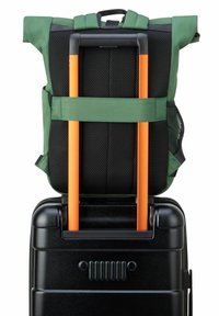 Zaino di tessuto verde con retro in rete, fissato su una valigia nera con ruote dotata di maniglie arancioni e finitura liscia e lucida.