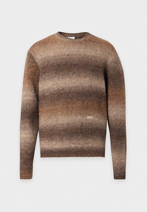 Jersey de rayas marrones y beige, de manga larga y cuello redondo, con un pequeño logotipo de ARKK en el pecho, sobre un fondo blanco liso.