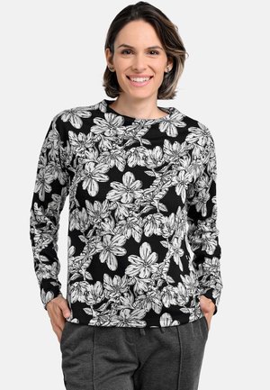 Floral long-sleeve top in black with white floral pattern. Round neckline, soft fabric, fitted cuffs, and relaxed fit. Paired with gray pants.
