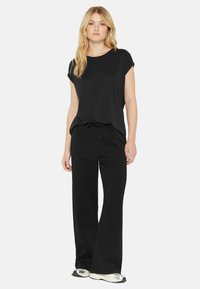 Black short-sleeved top with a round neckline, paired with black wide-leg pants. Soft, smooth fabric with a relaxed fit; drawstring waist detail.